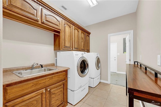 washroom featuring light tile patterned flooring, washing machine and dryer, a sink, visible vents, and cabinet space