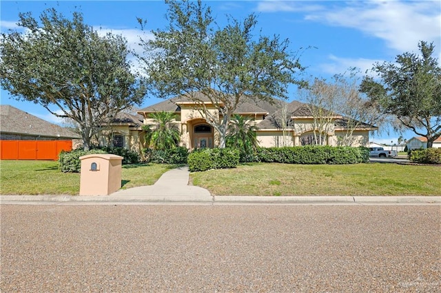 mediterranean / spanish-style home featuring a front yard, fence, and stucco siding