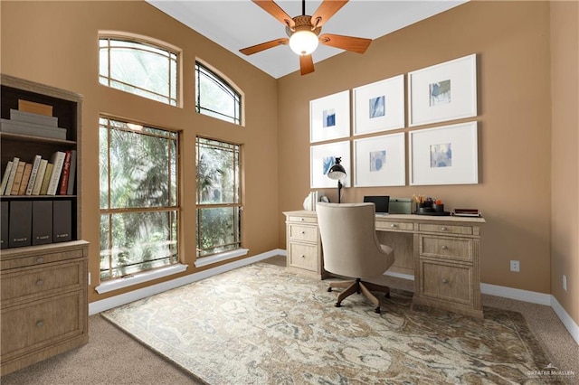 office space with light carpet, baseboards, and a ceiling fan