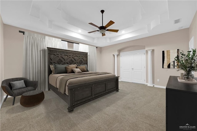 bedroom with carpet floors, a raised ceiling, visible vents, ornate columns, and baseboards