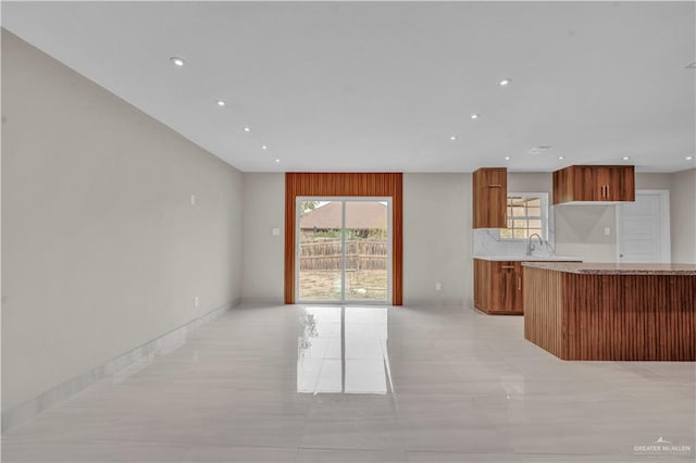 kitchen featuring open floor plan, light countertops, brown cabinetry, and recessed lighting