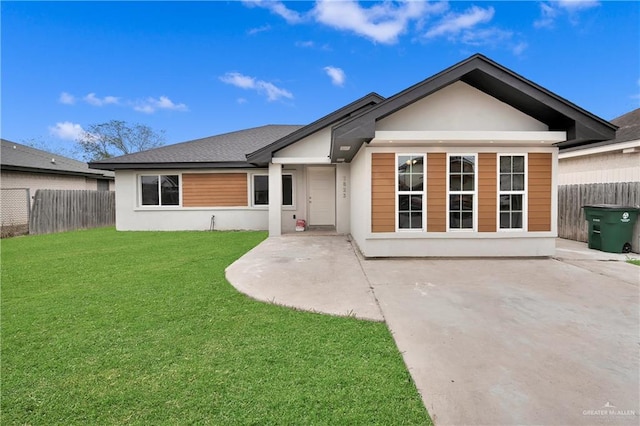 view of front of property with a patio area, fence, stucco siding, and a front yard