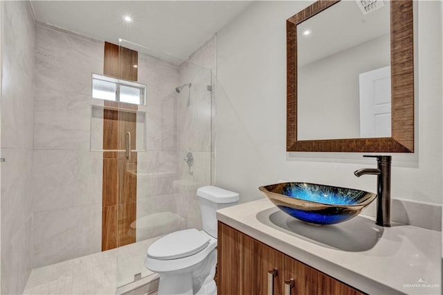 full bath featuring toilet, visible vents, a tile shower, and vanity