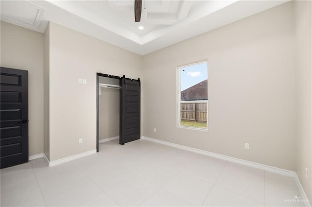 unfurnished bedroom with coffered ceiling, light tile patterned floors, a barn door, and ceiling fan