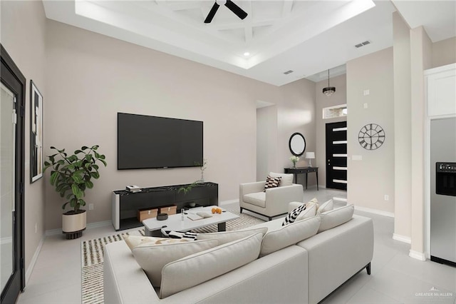 living room featuring a raised ceiling, a high ceiling, coffered ceiling, and ceiling fan