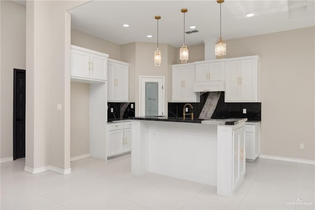 kitchen with white cabinetry, tasteful backsplash, hanging light fixtures, light tile patterned floors, and a kitchen island with sink