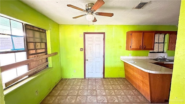 kitchen with a textured ceiling, tasteful backsplash, ceiling fan, and sink