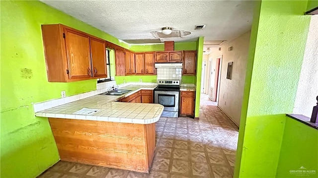 kitchen with kitchen peninsula, a textured ceiling, sink, electric range, and tile countertops