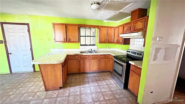 kitchen featuring tile countertops, backsplash, stainless steel electric stove, sink, and kitchen peninsula