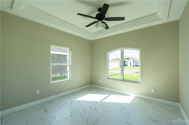 spare room with marble finish floor, baseboards, a raised ceiling, and a ceiling fan