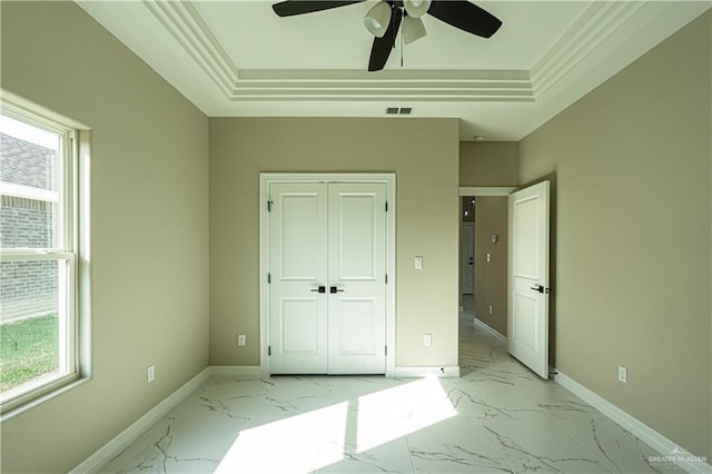 unfurnished bedroom with marble finish floor, a tray ceiling, and baseboards