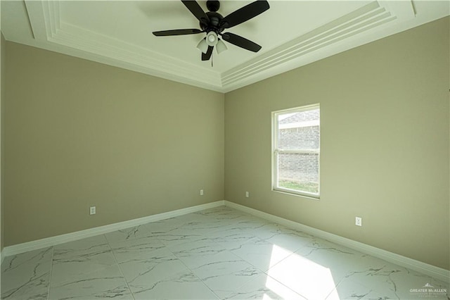 empty room with a tray ceiling, marble finish floor, ceiling fan, and baseboards