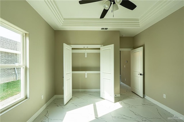 unfurnished bedroom with marble finish floor, multiple windows, baseboards, and a tray ceiling