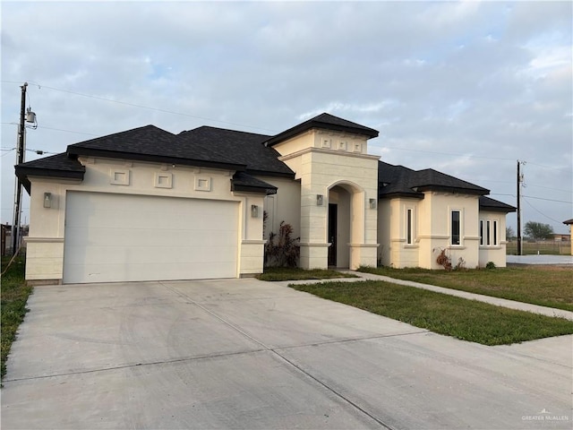 view of front facade with a garage, driveway, roof with shingles, a front lawn, and stucco siding