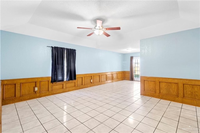 tiled empty room with a raised ceiling and ceiling fan