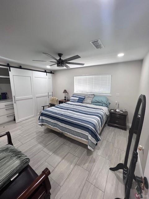 bedroom with a barn door and ceiling fan