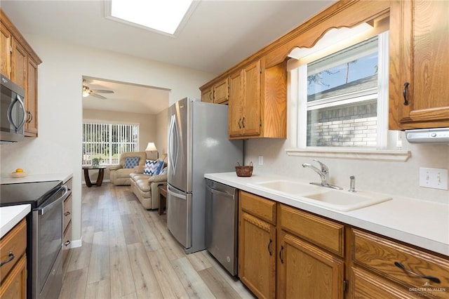 kitchen with stainless steel appliances, light hardwood / wood-style flooring, ceiling fan, and sink