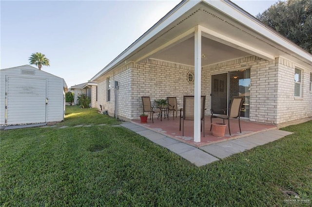 rear view of property with a lawn, a patio, and a shed