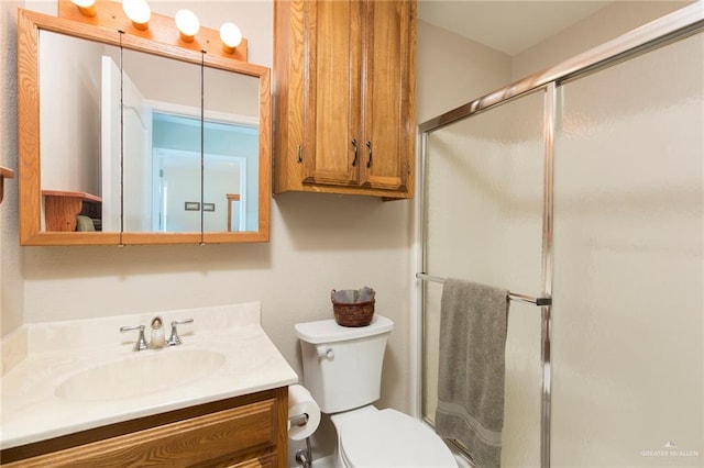 bathroom featuring a shower with door, vanity, and toilet