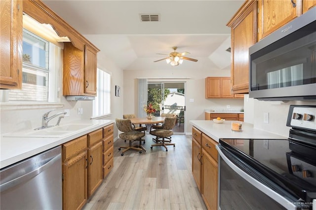 kitchen featuring light wood-type flooring, stainless steel appliances, vaulted ceiling, ceiling fan, and sink