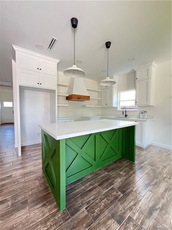 808 E Evans Ave, Pharr, TX 78577 - kitchen featuring premium range hood, white cabinetry, wood finished floors, a center island, and pendant lighting