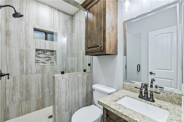 bathroom with toilet, vanity, and a tile shower