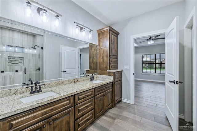 bathroom with double vanity, a sink, a shower stall, and ceiling fan