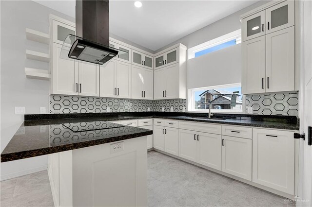 kitchen with decorative backsplash, white cabinetry, sink, and island range hood