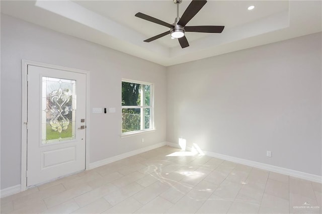 interior space with a raised ceiling and ceiling fan