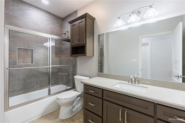 full bathroom featuring tile patterned flooring, vanity, toilet, and bath / shower combo with glass door