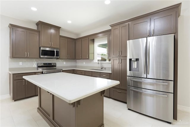 kitchen featuring a center island, backsplash, sink, appliances with stainless steel finishes, and dark brown cabinets