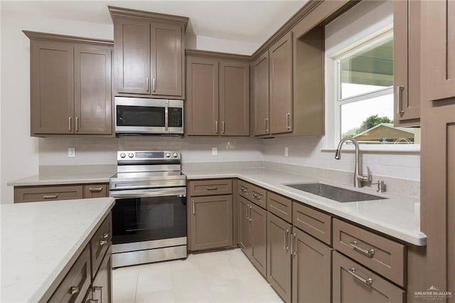 kitchen featuring appliances with stainless steel finishes, backsplash, light tile patterned floors, and sink