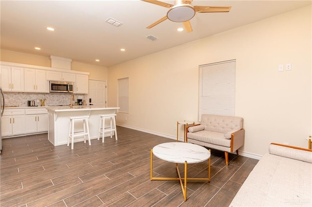 living room featuring ceiling fan and dark wood-type flooring