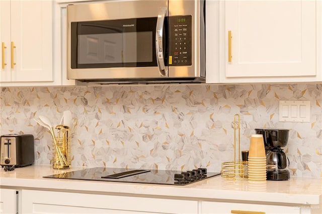 kitchen featuring black electric cooktop, white cabinetry, and decorative backsplash