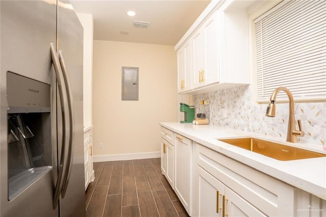 kitchen featuring electric panel, stainless steel fridge with ice dispenser, sink, and white cabinets