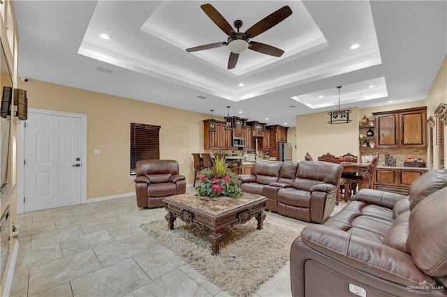 living room featuring a tray ceiling and ceiling fan