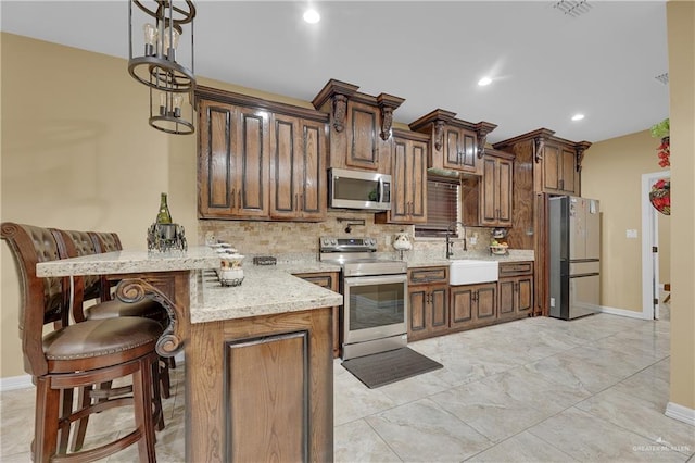 kitchen with a breakfast bar, sink, decorative light fixtures, kitchen peninsula, and stainless steel appliances