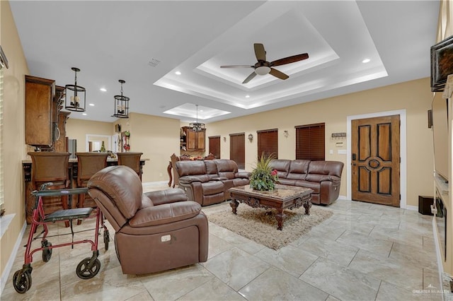 living room with ceiling fan and a tray ceiling