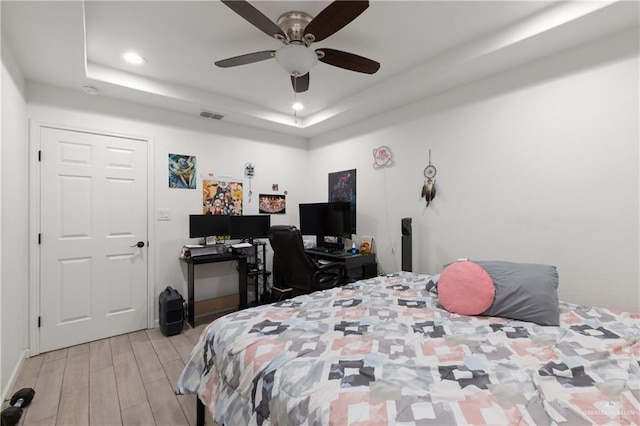 bedroom featuring ceiling fan, recessed lighting, visible vents, light wood finished floors, and a raised ceiling