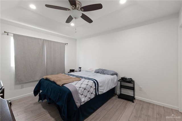 bedroom featuring recessed lighting, a raised ceiling, ceiling fan, wood finished floors, and baseboards