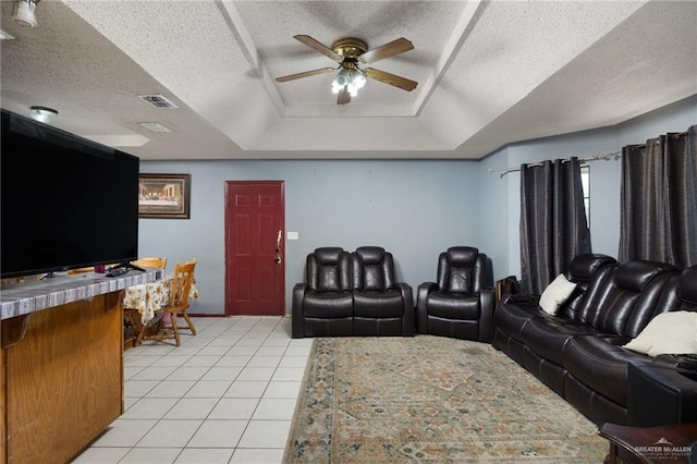 tiled home theater room with a textured ceiling, a tray ceiling, and ceiling fan