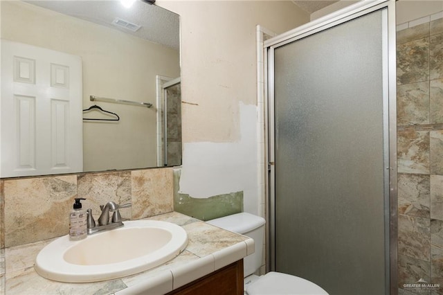 bathroom with vanity, tasteful backsplash, toilet, and walk in shower