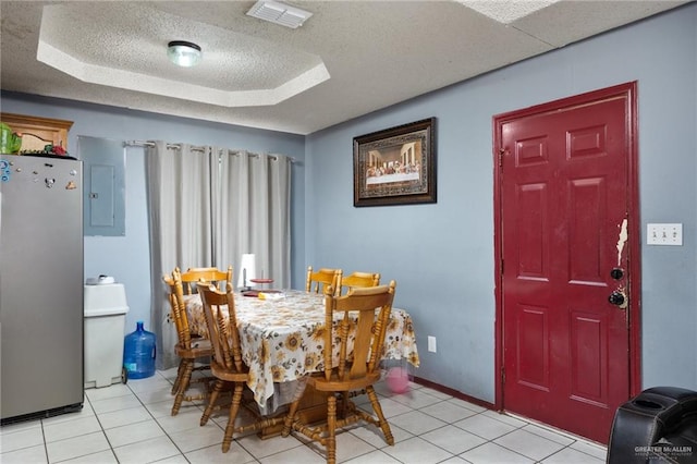 tiled dining area featuring a textured ceiling, electric panel, and a tray ceiling