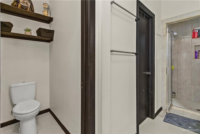 bathroom with tile patterned floors, toilet, and a shower with shower door