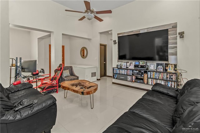 tiled living room featuring ceiling fan and a high ceiling