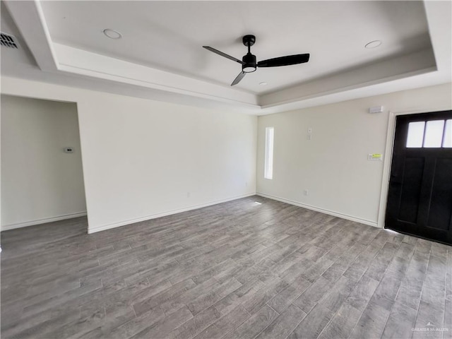 interior space with ceiling fan, a tray ceiling, and light hardwood / wood-style floors