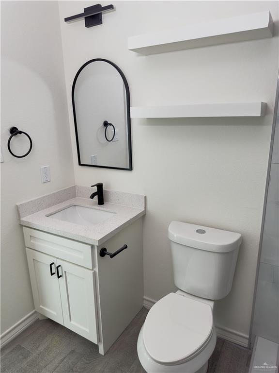 bathroom with toilet, hardwood / wood-style floors, and vanity