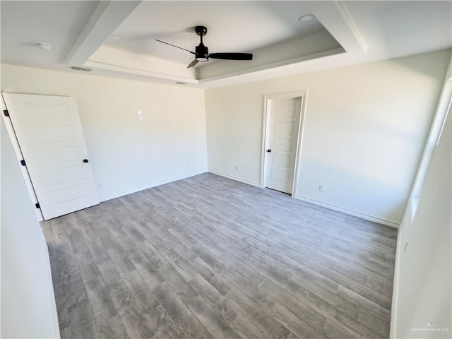 spare room featuring light hardwood / wood-style floors, a raised ceiling, and ceiling fan