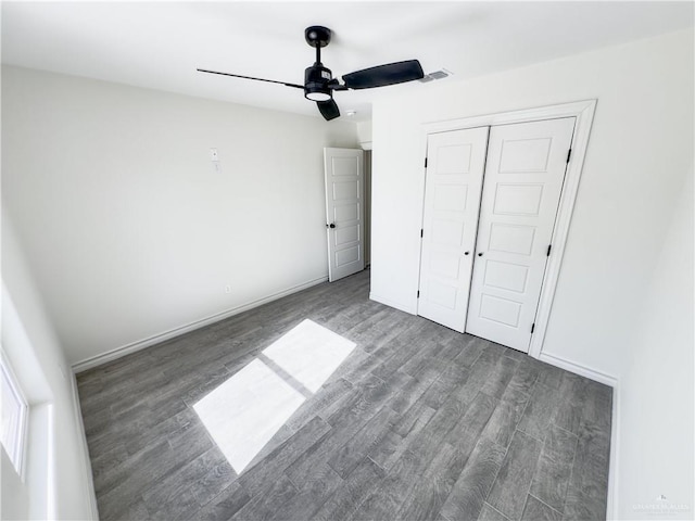 unfurnished bedroom featuring ceiling fan, a closet, and dark hardwood / wood-style flooring