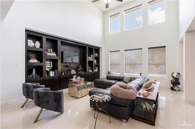 living room featuring ceiling fan, light tile patterned floors, and a high ceiling